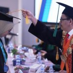 Rektor UIN Antasari Prof. Dr. H. Mujiburrahman, M.A. saat memindah tali topi toga wisudawati terbaik dari FUH atas nama Mutia Rahmah, S.Ag. (Foto: Tim Humas)