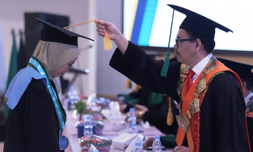 Rektor UIN Antasari Prof. Dr. H. Mujiburrahman, M.A. saat memindah tali topi toga wisudawati terbaik dari FUH atas nama Mutia Rahmah, S.Ag. (Foto: Tim Humas)