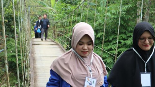 Dua mahasiswi saat melewati jembatan gantung bergoyang di Desa Haruyan Dayak (Foto:Humas/Achmad Maghfur)