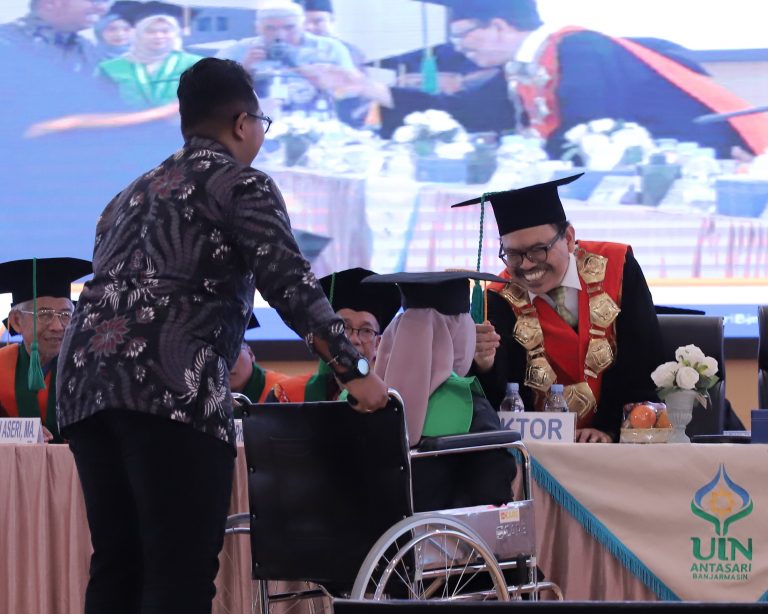 Rektor UIN Antasari Prof. Dr. H. Mujiburrahman, M.A. saat memindahkan tali topi toga Husnul Khazijah (Foto:Tim Humas)