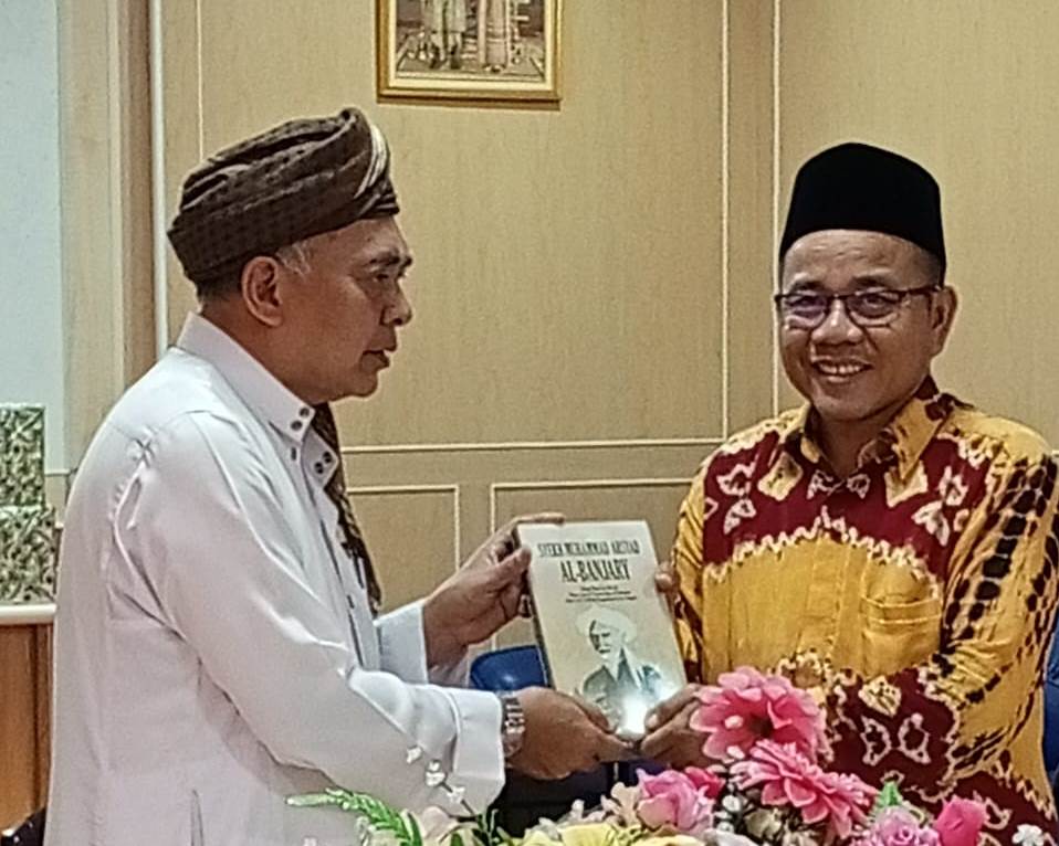 Dr. Nuryadin, M.Ag. saat menyerahkan hadiah buku Biografi Syekh Muhammad Arsyad Al-Banjari karya Zafry Zamzam