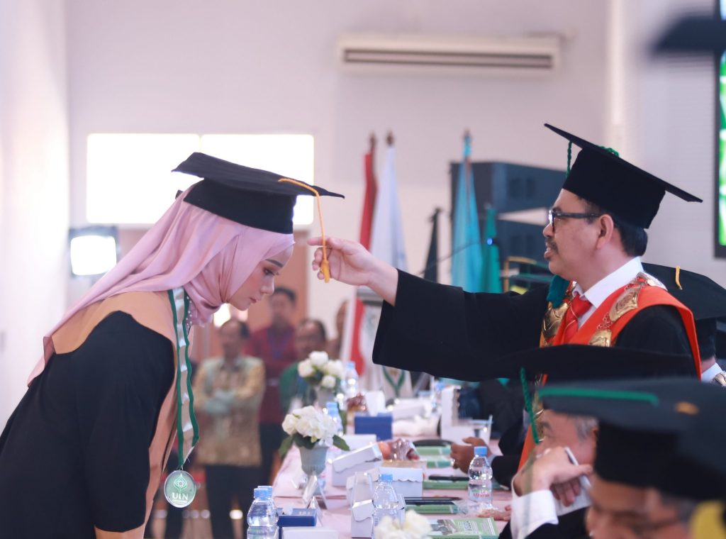 Rektor UIN Antasari Prof. Dr. H. Mujiburrahman, M.A. saat memindahkan tali topi toga wisudawati terbaik (Foto:Humas/Yulida Rifani)