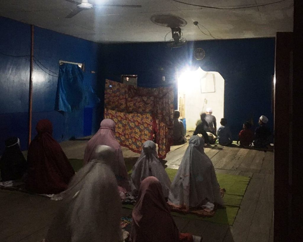 Hanya menggunakan kain seadanya sebagai pembatas saf, para mahasiswa KKN ajak anak-anak Desa Simpang Warga salat berjamaah (Foto:Julia)