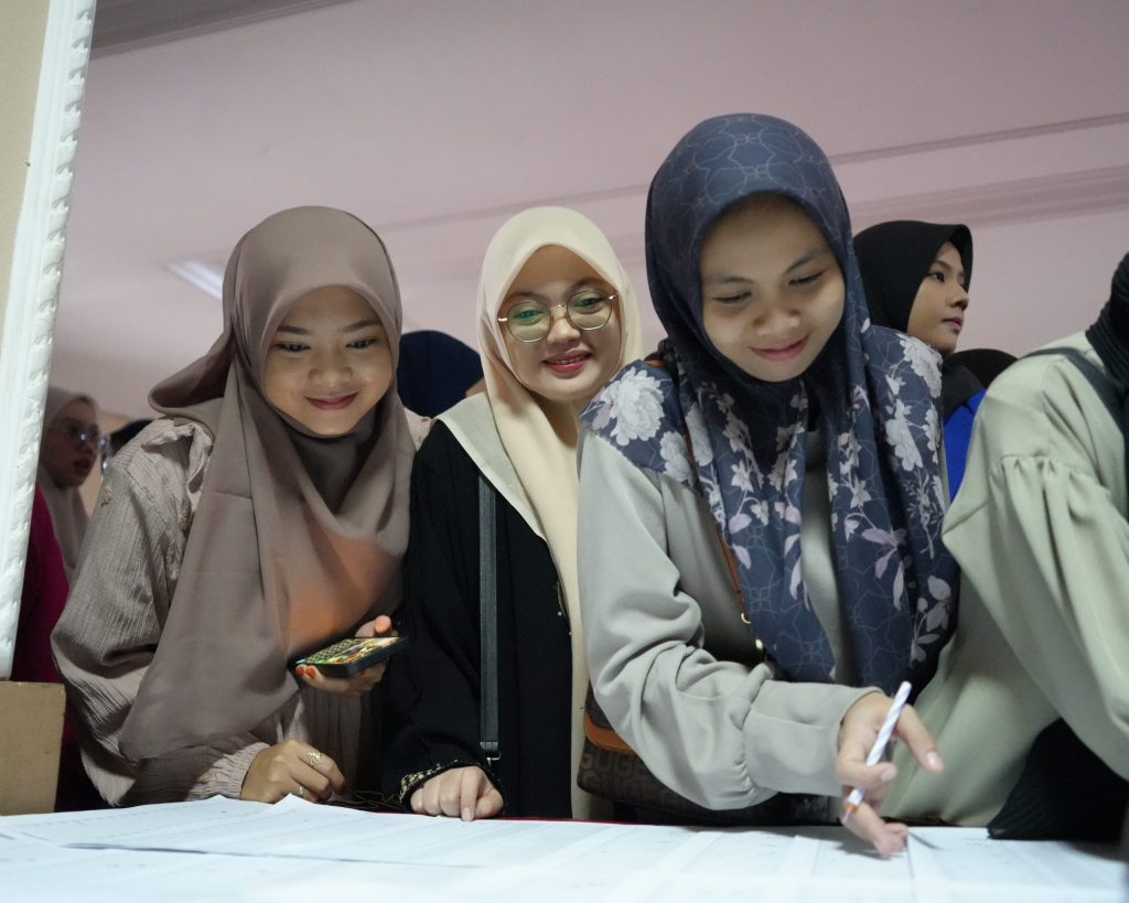 Para mahasiswi sedang mencari namanya di daftar registrasi (Foto:Humas/Achmad Magfur)