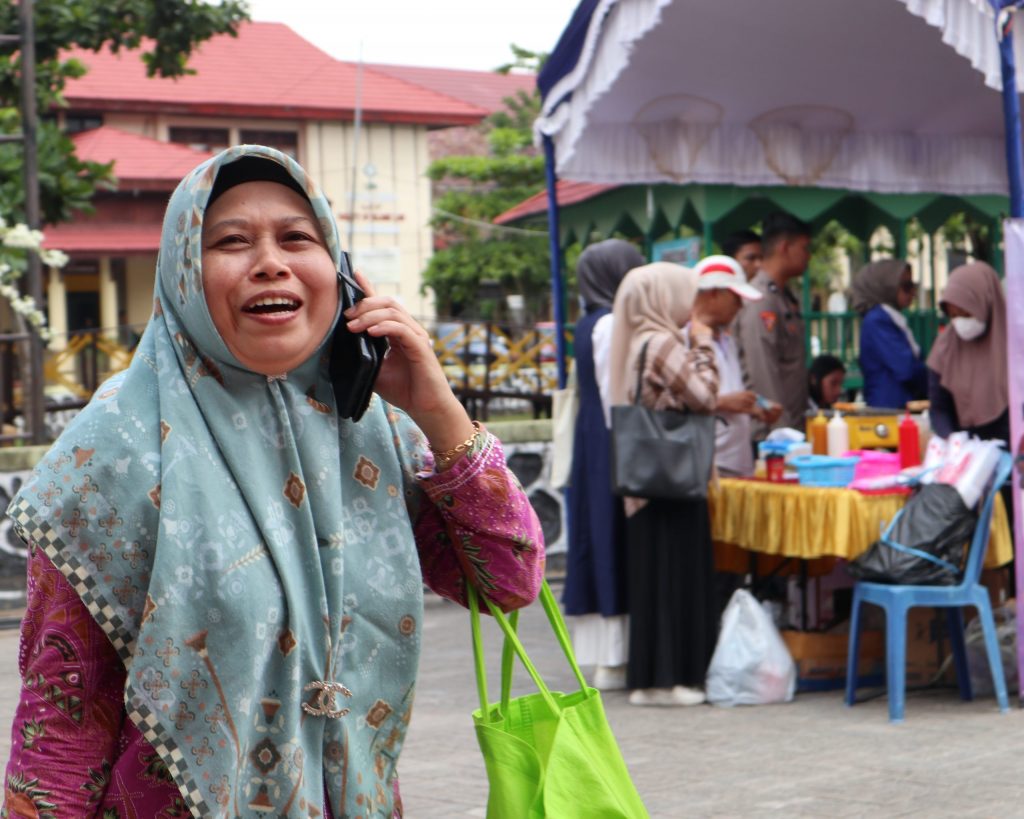 Seorang ibu tertangkap kamera ketika gembira menghubungi keluarganya bahwa ada pasar murah di Kampus 1 UIN Antasari (Foto:Humas/Achmad Magfur)