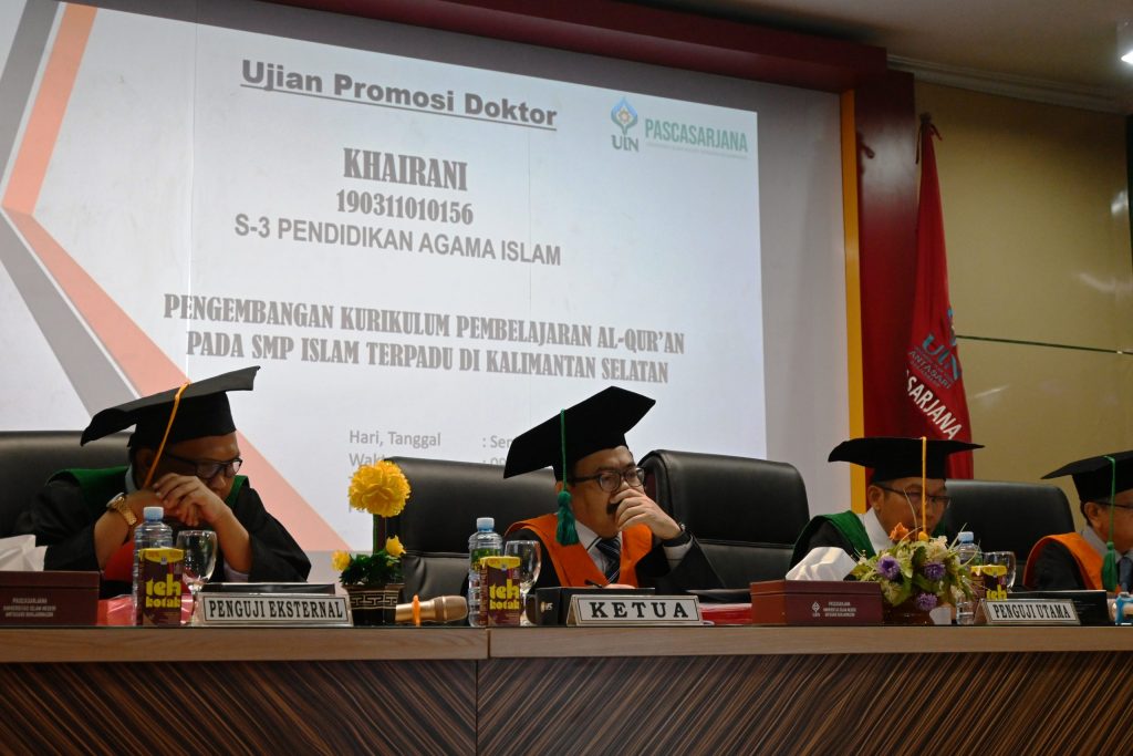 Para penguji saat menyaksikan presentasi promovendus di layar bagian bawah (Foto:Humas/Achmad Magfur)