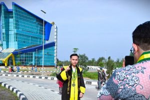 Akhmad Maulana Hafiz, S.E. saat berfoto berlatar Gedung Rektorat Kampus 2 (Foto Humas Jamal Ripani)