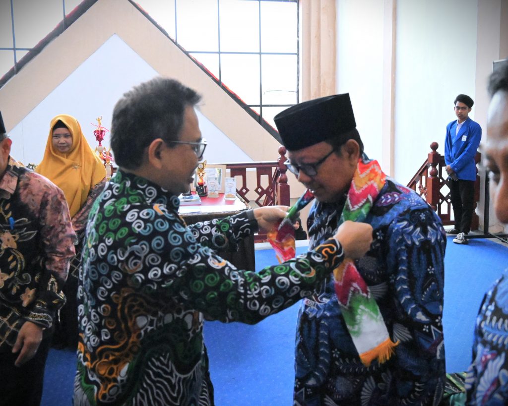 Rektor saat mengalungkan kain sasirangan atas kedatangan Asesor I (Foto:Humas)