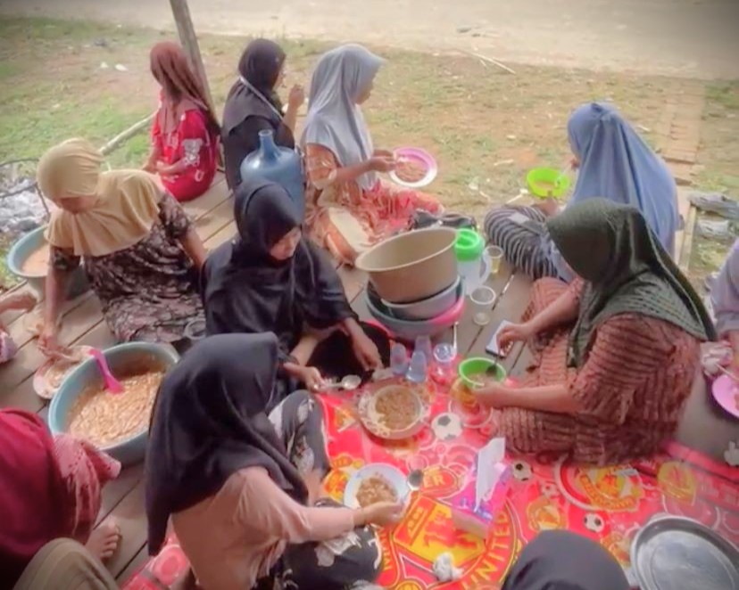 Para mahasiswa saat makan bubur baayak bersama ibu-ibu Desa Masiraan.