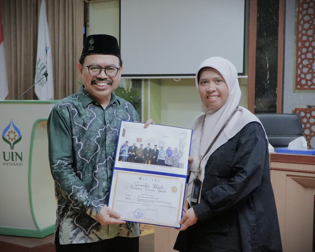 Rektor saat memberikan kenang-kenangan kepada Koordinator Pusat Humas dan Keterbukaan Informasi Noor Hasanah, S.Pd.I., M.A. (Foto:Humas/Rudy Hermawan)