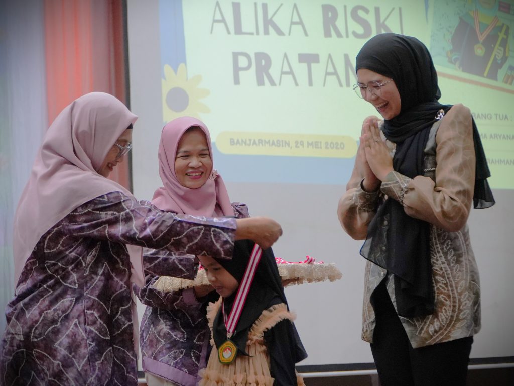 Ny. Rahimah Muhdi saat mengalungkan tanda alumni.
