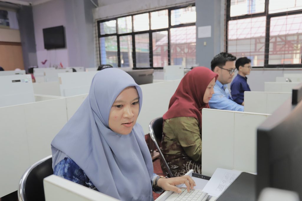 Thaibatun Nisa, M.Pd. saat bertugas melayani peserta.